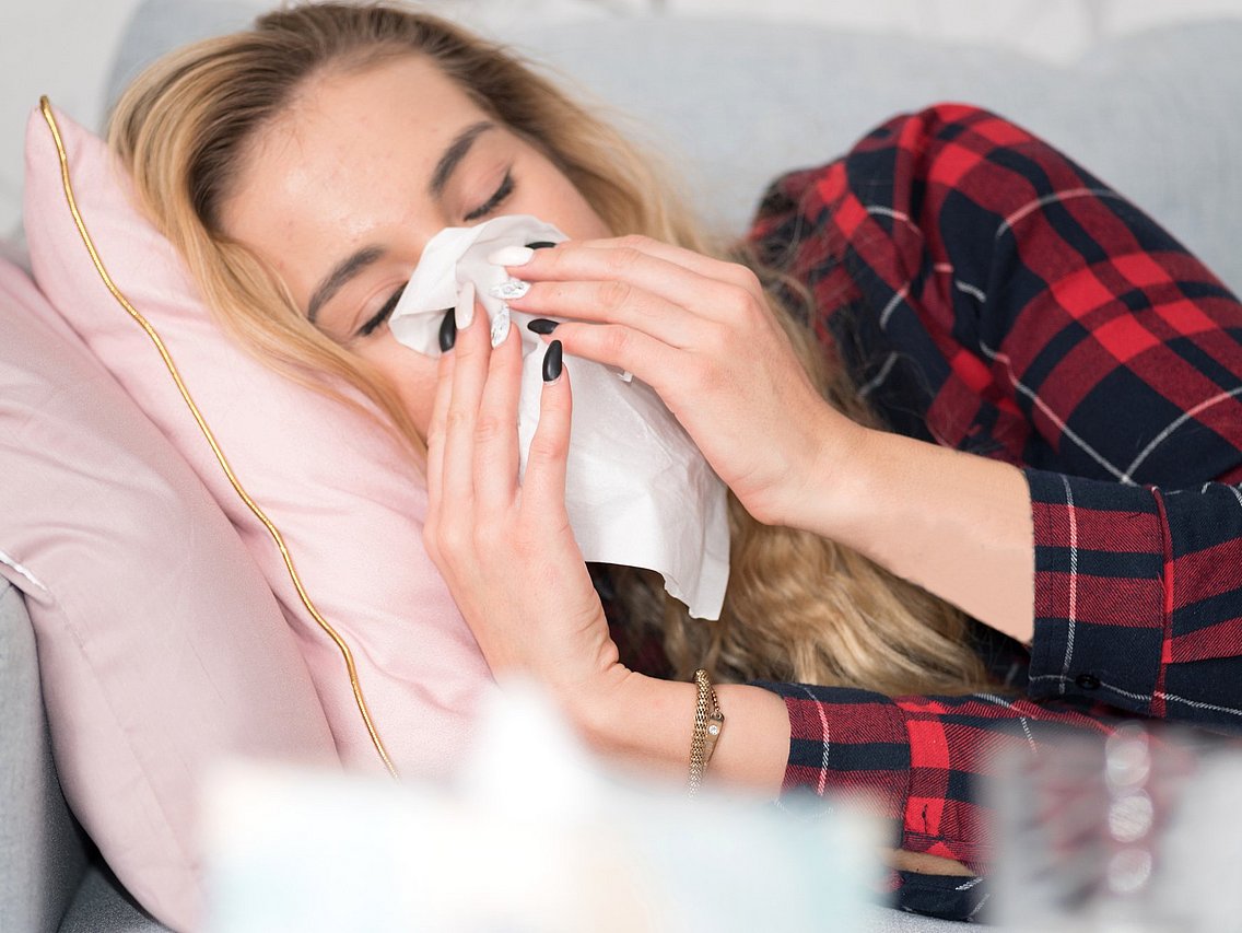 Frau mit einer Erkältung Eine erkältete Frau mit Schnupfen liegt krank im Bett. © studio v-zwoelf/adobe.stock